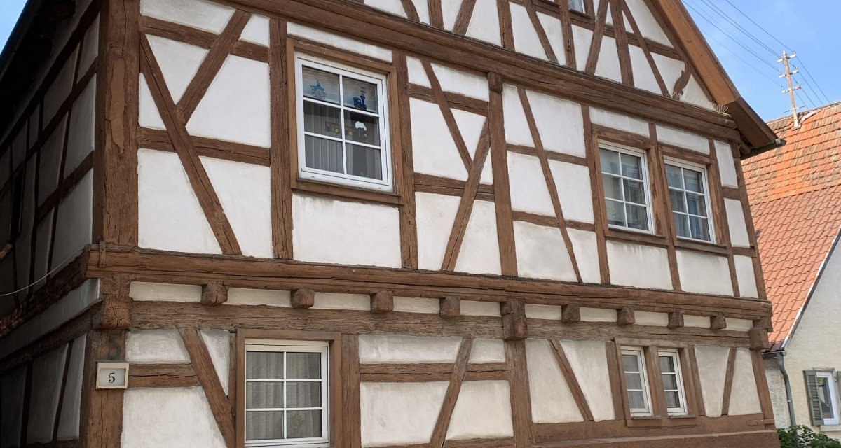 Fachwerkhaus mit braunen Balken und wei&szlig;em Putz, gro&szlig;es Holztor und mehrere Fenster. Historisches Geb&auml;ude unter blauem Himmel., &copy; Land der 1000 H&uuml;gel - Kraichgau-Stromberg