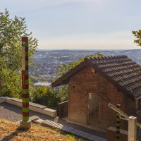 Kleines Backsteinhaus in den Metzinger Weinbergen, umgeben von Bäumen, mit Blick auf die Stadt im Hintergrund., © SMG Mende