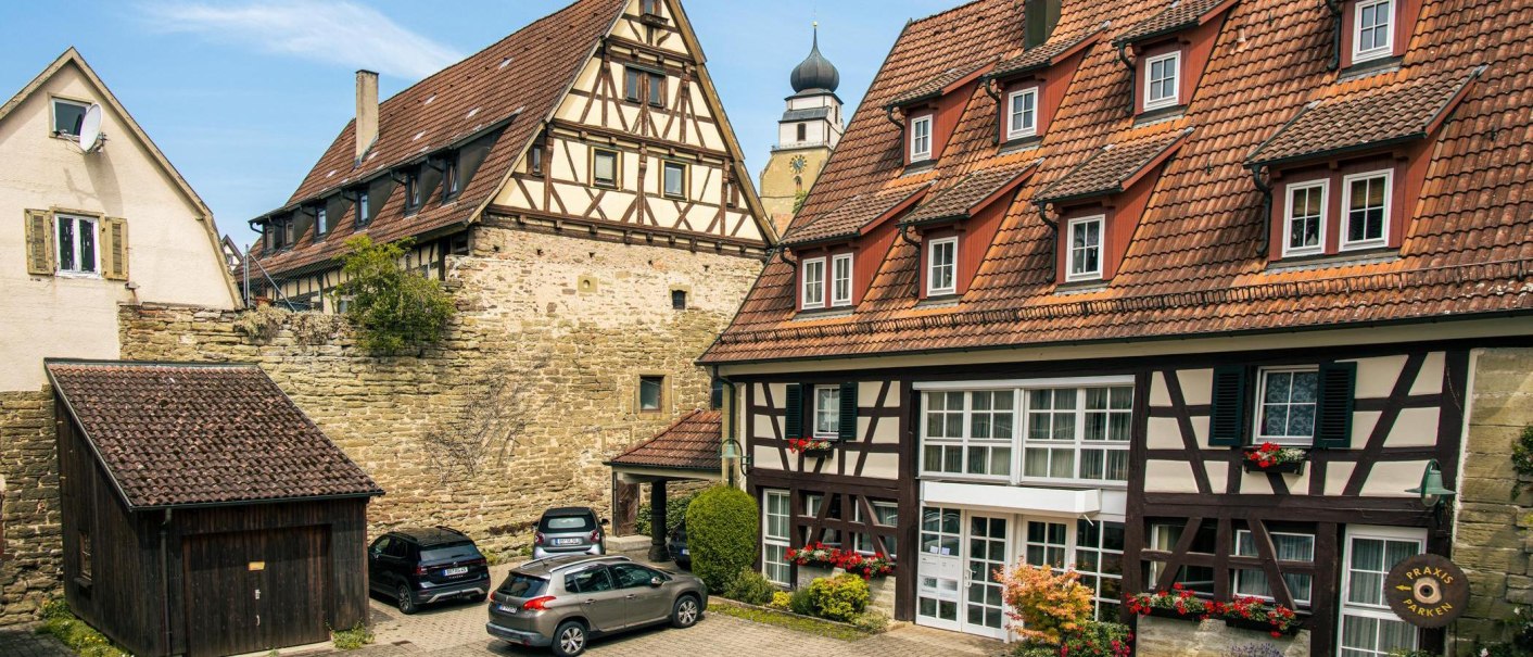 Fachwerkhäuser in der Altstadt von Herrenberg. Im Vordergrund sind Autos geparkt. Ein Kirchturm ist im Hintergrund sichtbar., © Stuttgart-Marketing GmbH, Sarah Schmid Fachwerkhäuser in der Altstadt von Herrenberg. Im Vordergrund sind Autos geparkt. Ein Kirchturm ist im Hintergrund sichtbar., © Stuttgart-Marketing GmbH, Sarah Schmid