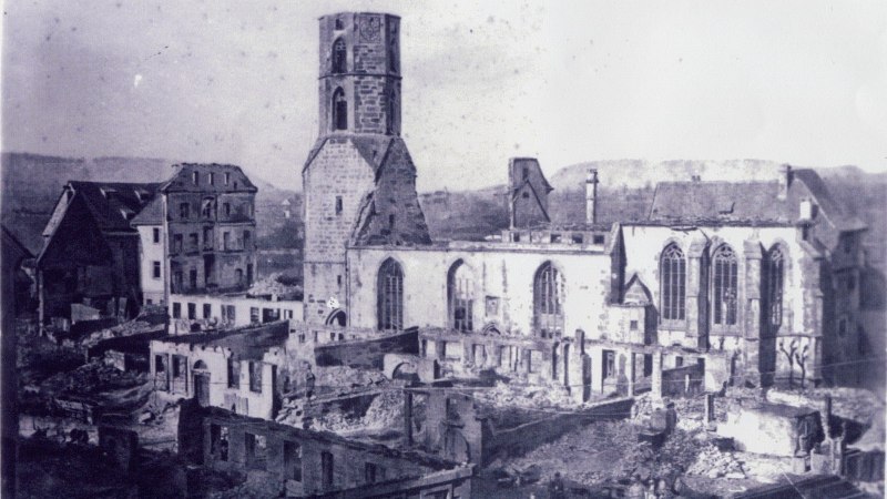 Eine Kirche und umliegende Geb&auml;ude zeigen schwere Sch&auml;den nach dem Stadtbrand von 1868. Ruinen und zerst&ouml;rte D&auml;cher sind sichtbar., &copy; Kirchenbezirk Schw&auml;bisch Hall-Gaildorf