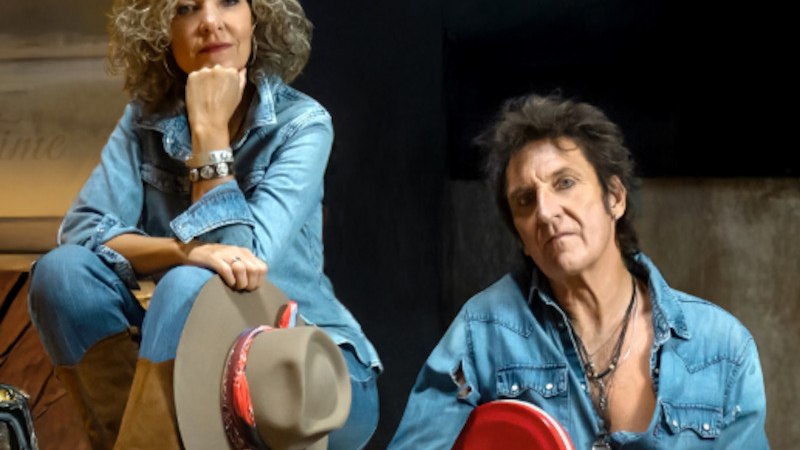 Zwei Personen in Jeanskleidung, die Frau sitzt mit einem Hut auf dem Knie, der Mann h&auml;lt eine rote E-Gitarre. Beide blicken in die Kamera., &copy; Scala Kultur Live gGmbH