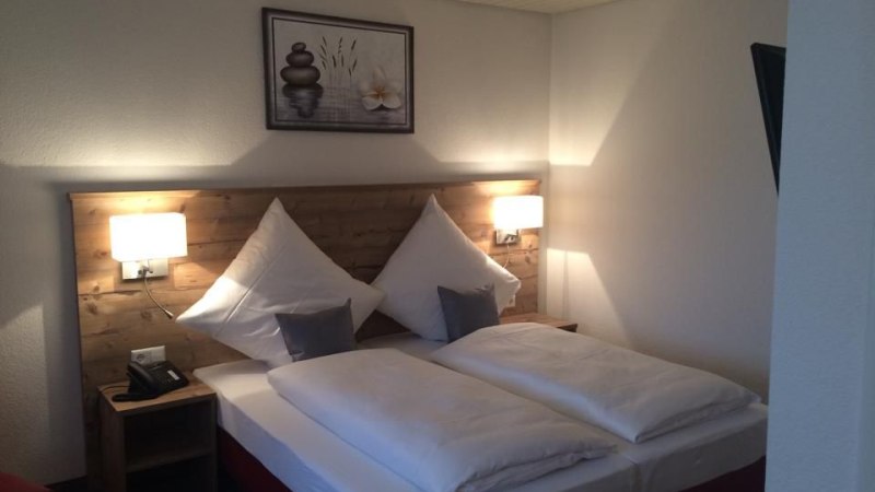 Gem&uuml;tliches Doppelzimmer mit Holzkopfteil, zwei Kissen, zwei Nachttischen und einem Bild an der Wand., &copy; Hotel Lamm Hegnach