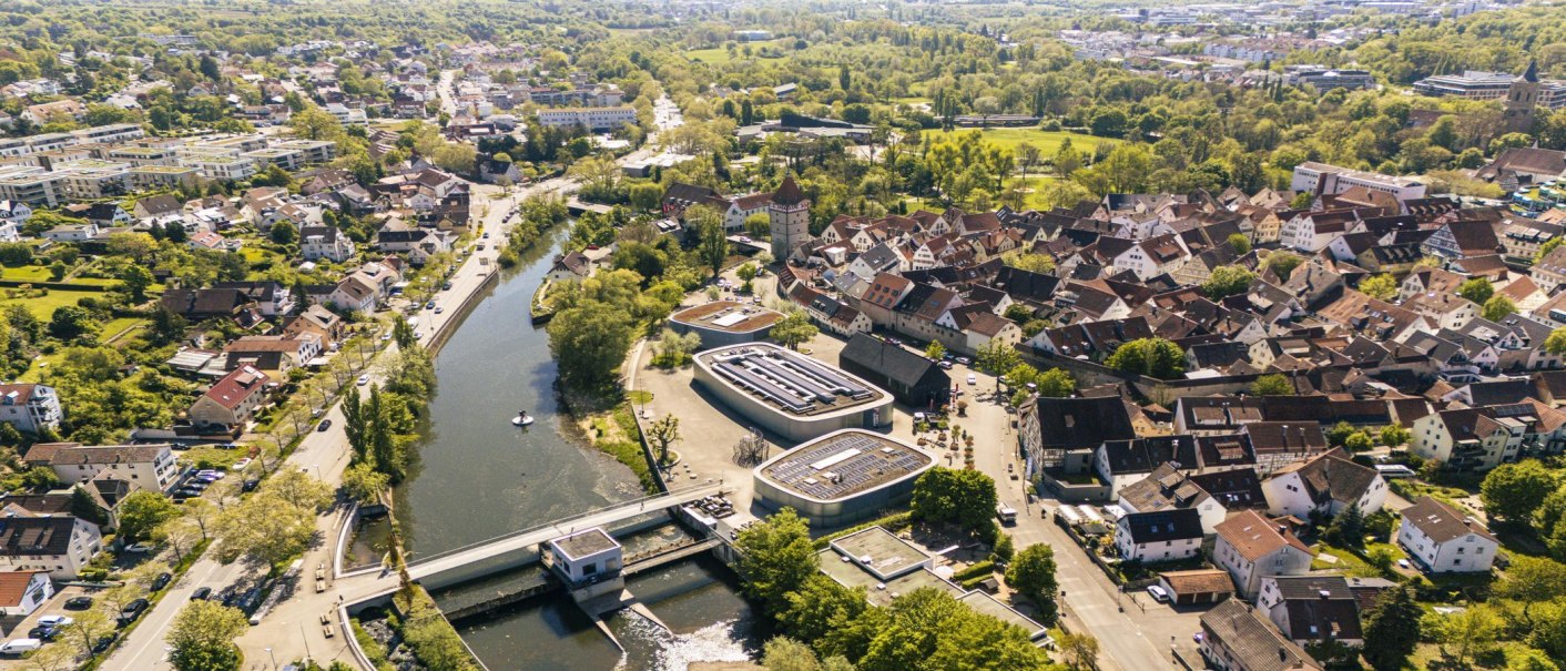 Luftaufnahme der Altstadt von Waiblingen mit dicht gedrängten Häusern, einem Fluss und viel Grün. Moderne Gebäude und Straßen sind ebenfalls sichtbar., © SMG, Sarah Schmid Luftaufnahme der Altstadt von Waiblingen mit dicht gedrängten Häusern, einem Fluss und viel Grün. Moderne Gebäude und Straßen sind ebenfalls sichtbar., © SMG, Sarah Schmid