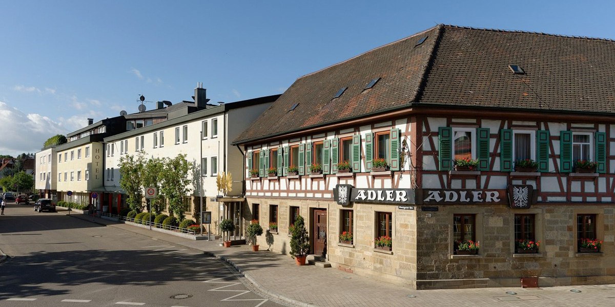 Das Hotel Adler zeigt ein traditionelles Fachwerkgebäude mit grünen Fensterläden und modernen Anbauten in einer ruhigen Straße., © Ringhotel Adler Asperg