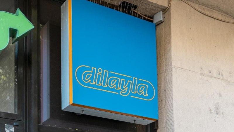 Blaues Schild mit gelber Aufschrift 'dilayla' an einer Gebäudewand, daneben ein grüner Pfeil., © Stuttgart Marketing GmbH, Sarah Schmid Blaues Schild mit gelber Aufschrift 'dilayla' an einer Gebäudewand, daneben ein grüner Pfeil., © Stuttgart Marketing GmbH, Sarah Schmid