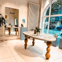 Modernes Studio mit Holztisch, Spiegel und Dekorationen. Gro&szlig;e Fensterfront mit Blick auf die Stra&szlig;e. Pflanzen und Kunstobjekte als Dekoration., &copy; Goldmarlen