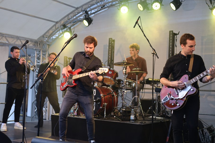 Eine Band spielt auf einer Bühne. Musiker mit Gitarren, Trompeten und Schlagzeug. Bühnenbeleuchtung und Mikrofone sind sichtbar., © Stadt Nürtingen Eine Band spielt auf einer Bühne. Musiker mit Gitarren, Trompeten und Schlagzeug. Bühnenbeleuchtung und Mikrofone sind sichtbar., © Stadt Nürtingen