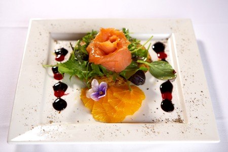 Gourmet-Vorspeise mit Lachs, Orangen, Salat und essbarer Blüte, kunstvoll auf einem weißen Teller angerichtet., © Jeanette Bender Gourmet-Vorspeise mit Lachs, Orangen, Salat und essbarer Blüte, kunstvoll auf einem weißen Teller angerichtet., © Jeanette Bender