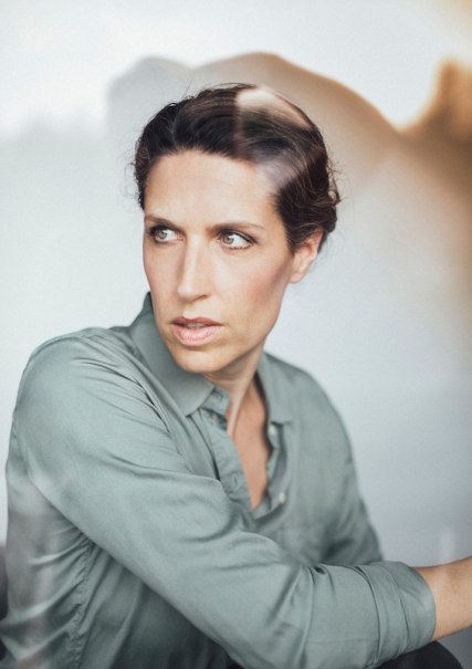 Frau in grauem Hemd blickt nach links, mit ernstem Gesichtsausdruck. Der Hintergrund ist unscharf, was den Fokus auf ihr Gesicht lenkt., © Scala Kultur Live gGmbH Frau in grauem Hemd blickt nach links, mit ernstem Gesichtsausdruck. Der Hintergrund ist unscharf, was den Fokus auf ihr Gesicht lenkt., © Scala Kultur Live gGmbH