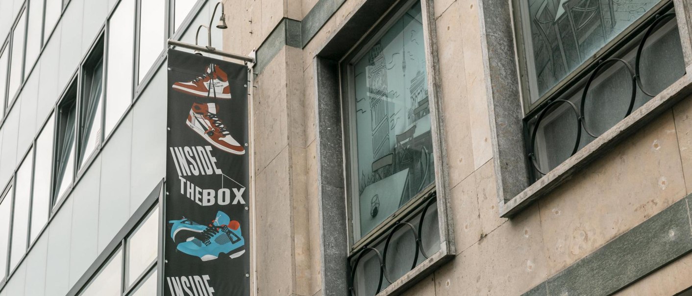 Fassade eines Gebäudes mit einem Schild 'Inside The Box' und einem gezeichneten Café im Fenster., © SMG, Sarah Schmid