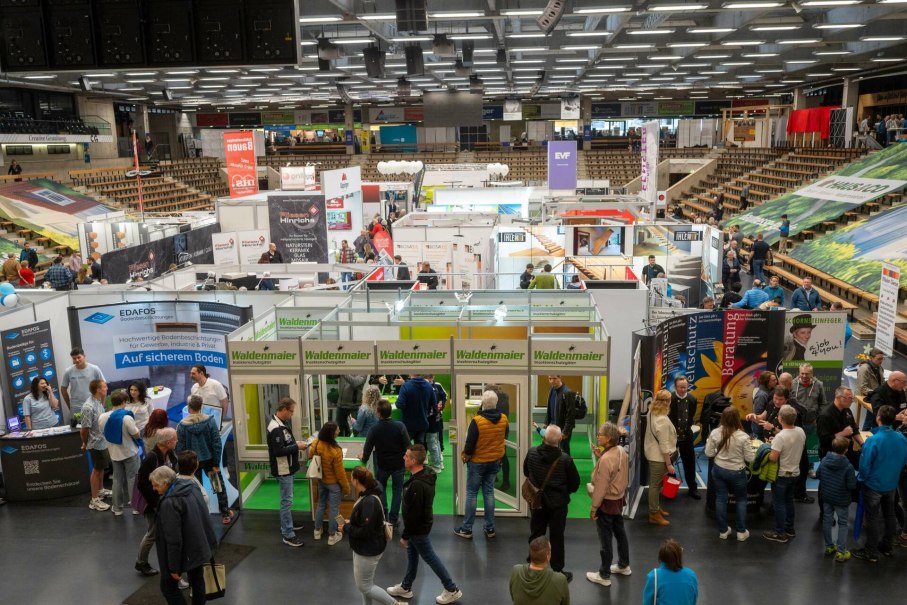 Besucher auf einer Baumesse mit zahlreichen Ständen und Ausstellern, die Produkte und Dienstleistungen rund ums Bauen und Wohnen präsentieren.