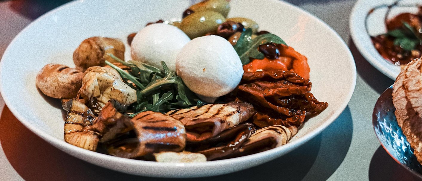 Ein Teller mit Antipasti: Mozzarella, gegrilltes Gemüse, Rucola und Oliven. Farbenfrohe und appetitliche Präsentation., © Italo Disco, Stuttgart Ein Teller mit Antipasti: Mozzarella, gegrilltes Gemüse, Rucola und Oliven. Farbenfrohe und appetitliche Präsentation., © Italo Disco, Stuttgart