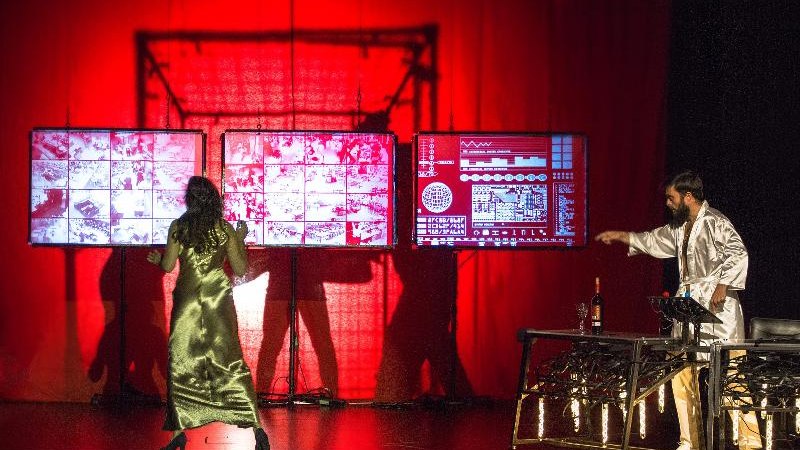 Zwei Personen auf einer Bühne mit rotem Hintergrund. Eine Frau in einem goldenen Kleid steht vor Bildschirmen, ein Mann in einem weißen Mantel zeigt auf etwas., © Backnang Zwei Personen auf einer Bühne mit rotem Hintergrund. Eine Frau in einem goldenen Kleid steht vor Bildschirmen, ein Mann in einem weißen Mantel zeigt auf etwas., © Backnang