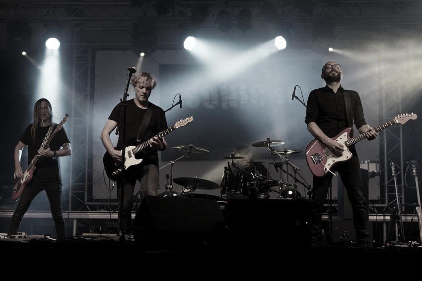 Eine Band performt auf einer B&uuml;hne mit Gitarren und Schlagzeug, umgeben von Scheinwerfern und Nebel., &copy; Foto_(c)_The SONIC Spy