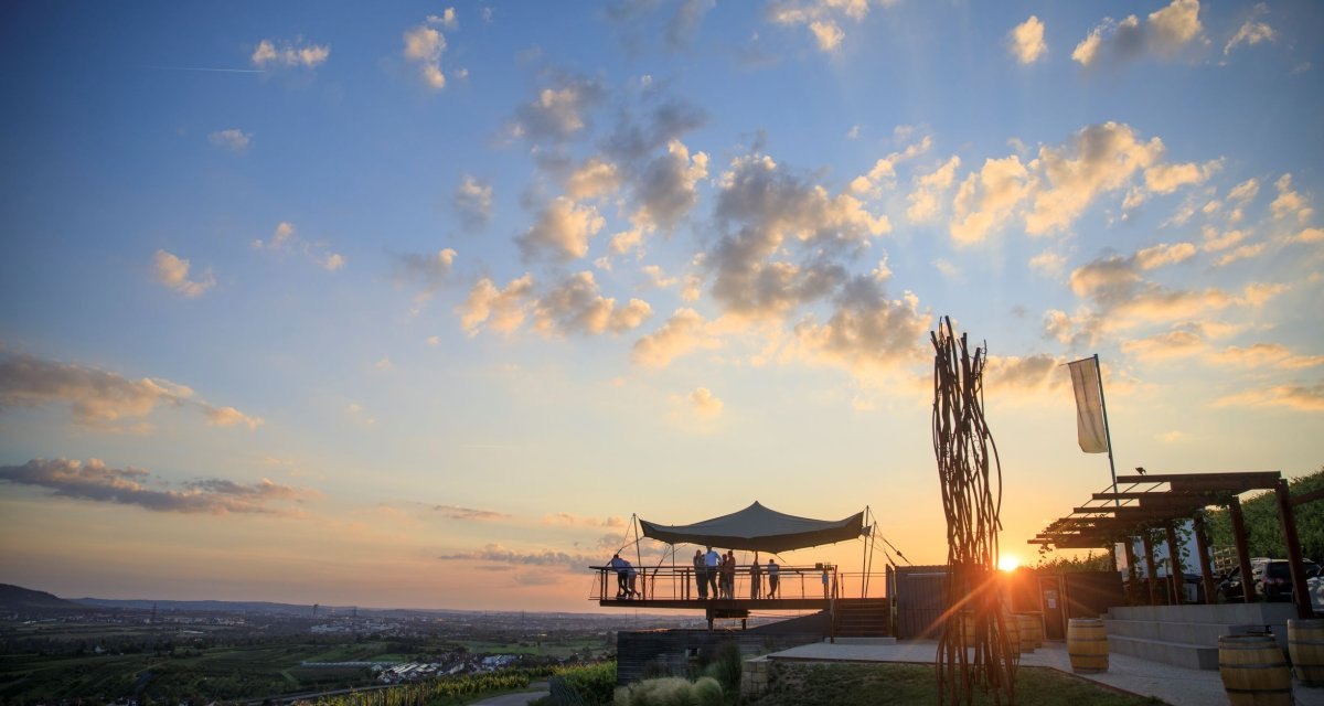 Sonnenuntergang über einer Terrasse mit Aussichtspunkt. Menschen genießen die Aussicht auf Weinberge und die Landschaft im Remstal., © Stoppel Sonnenuntergang über einer Terrasse mit Aussichtspunkt. Menschen genießen die Aussicht auf Weinberge und die Landschaft im Remstal., © Stoppel
