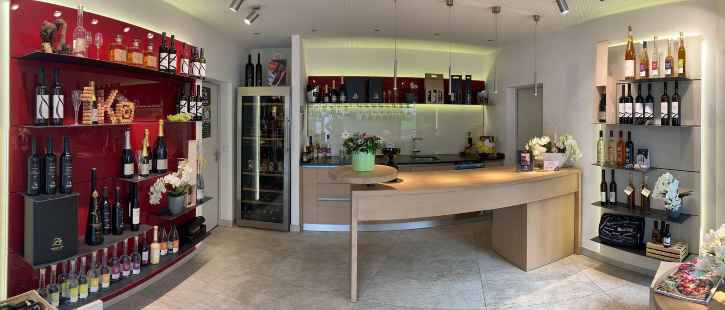 Moderne Vinothek mit Weinregalen, Flaschen, Gläsern und Dekorationen. Helle Beleuchtung und einladendes Ambiente., © Weingut Zaiß Moderne Vinothek mit Weinregalen, Flaschen, Gläsern und Dekorationen. Helle Beleuchtung und einladendes Ambiente., © Weingut Zaiß