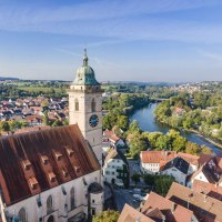 Drohnenansicht der Stadtkirche am Neckar, umgeben von roten Dächern und grüner Landschaft. Der Fluss schlängelt sich durch die Stadt., © Stadplanungsamt Stadt Nürtingen; artismedia GmbH/ Olaf Kühl Drohnenansicht der Stadtkirche am Neckar, umgeben von roten Dächern und grüner Landschaft. Der Fluss schlängelt sich durch die Stadt., © Stadplanungsamt Stadt Nürtingen; artismedia GmbH/ Olaf Kühl