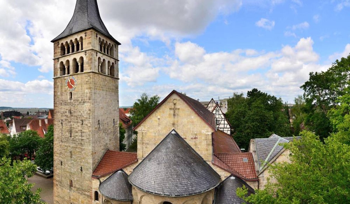 Historische Kirche mit hohem Turm und Spitzdach, umgeben von Bäumen und Fachwerkhäusern, unter einem bewölkten Himmel., © Natur.Nah. Schönbuch & Heckengäu