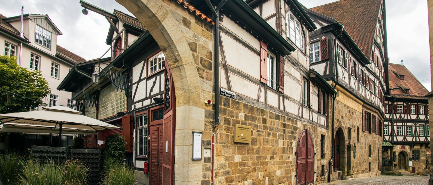 Historische Fachwerkhäuser in Esslingen mit einem Torbogen und gemütlichem Außenbereich. Die Architektur zeigt traditionelle Bauweise., © Stuttgart-Marketing GmbH, Sarah Schmid Historische Fachwerkhäuser in Esslingen mit einem Torbogen und gemütlichem Außenbereich. Die Architektur zeigt traditionelle Bauweise., © Stuttgart-Marketing GmbH, Sarah Schmid