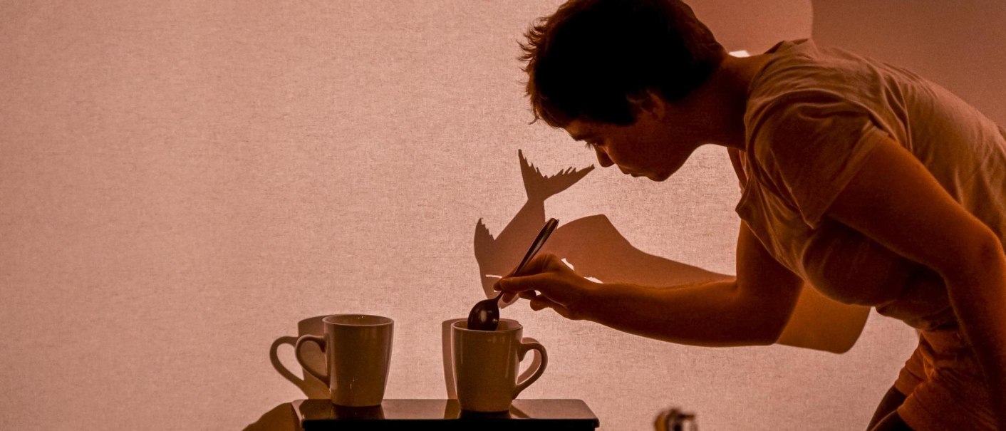 Person rührt in einer Tasse, projiziert Schatten auf Leinwand. Kreatives Spiel mit Licht und Schatten., © FITZ! Stuttgart