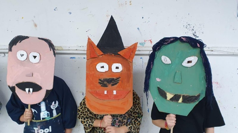 Drei Kinder präsentieren bunte, selbstgemachte Tiermasken aus Pappe. Die Masken sind fantasievoll gestaltet und zeigen verschiedene Tiergesichter., © Kunstschule Labyrinth