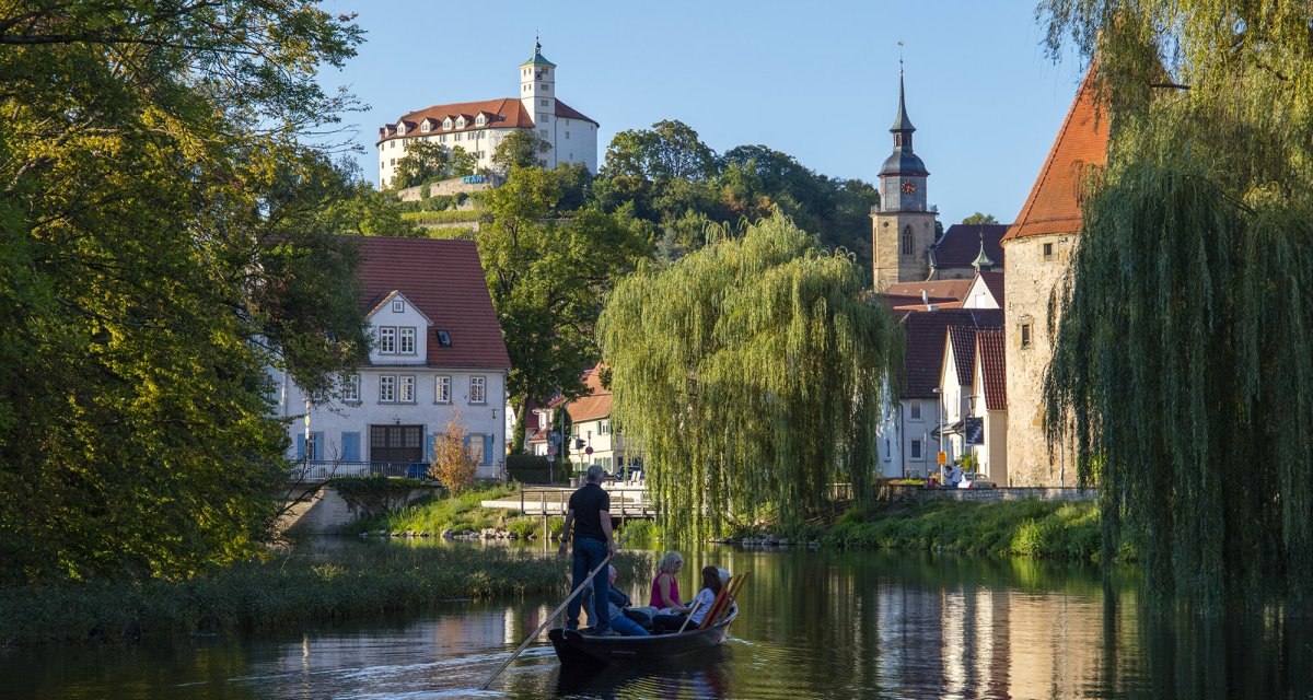 Ein Stocherkahn auf einem Fluss in Vaihingen an der Enz, umgeben von historischen Gebäuden und Bäumen. Im Hintergrund ist eine Burg zu sehen., © Stadt Vaihingen an der Enz Ein Stocherkahn auf einem Fluss in Vaihingen an der Enz, umgeben von historischen Gebäuden und Bäumen. Im Hintergrund ist eine Burg zu sehen., © Stadt Vaihingen an der Enz