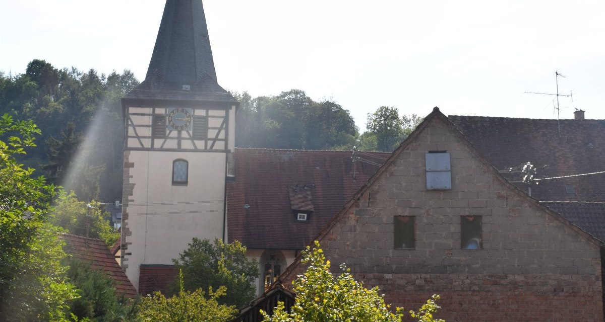 Kirchturm der Johanneskirche mit Fachwerk, umgeben von B&auml;umen und alten Geb&auml;uden. Der Himmel ist klar und sonnig., &copy; Land der 1000 H&uuml;gel - Kraichgau-Stromberg
