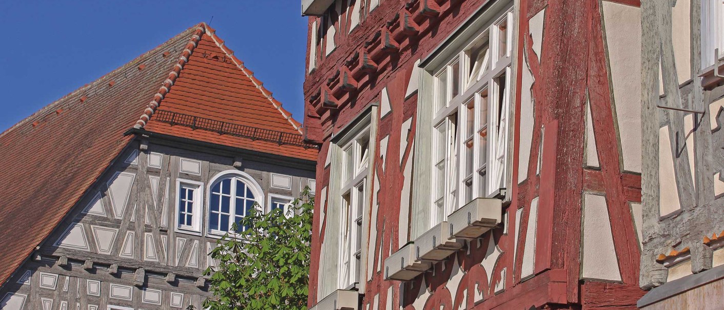 Fachwerkhäuser mit roten und grauen Balken, weiße Fenster und ein rotes Ziegeldach vor klarem, blauem Himmel., © Stadt Vaihingen an der Enz Fachwerkhäuser mit roten und grauen Balken, weiße Fenster und ein rotes Ziegeldach vor klarem, blauem Himmel., © Stadt Vaihingen an der Enz
