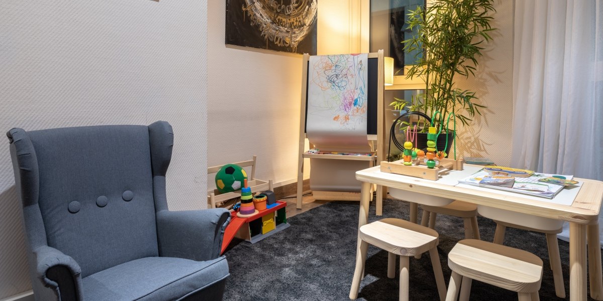 Gemütliche Kinderspielecke mit Tisch, Stühlen, Spielzeug, Malutensilien und einem Sessel. Eine Pflanze und ein Bild im Hintergrund ergänzen die Einrichtung., © Hotel Princess
