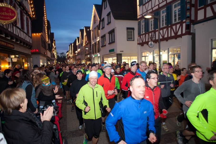 Menschenmengen laufen durch eine festlich beleuchtete Altstadtstraße beim Silvesterlauf. Zuschauer applaudieren am Straßenrand., © © Thomas Kaltenecker Menschenmengen laufen durch eine festlich beleuchtete Altstadtstraße beim Silvesterlauf. Zuschauer applaudieren am Straßenrand., © © Thomas Kaltenecker