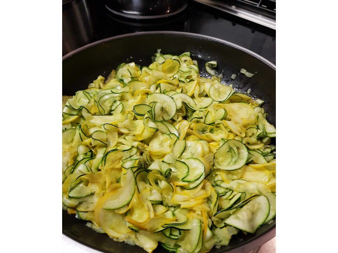 In einer Pfanne werden gelbe und grüne Zucchinischeiben gekocht. Sie sind dünn geschnitten und gleichmäßig verteilt., © Kultweine-Kochwelten-Kunstücke - Kochschule Sonja Lenz In einer Pfanne werden gelbe und grüne Zucchinischeiben gekocht. Sie sind dünn geschnitten und gleichmäßig verteilt., © Kultweine-Kochwelten-Kunstücke - Kochschule Sonja Lenz