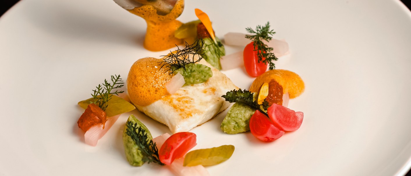 Heilbutt mit Avocado, Radieschen und Schaum kunstvoll auf weißem Teller angerichtet, mit Löffel serviert., © Hupperts Heilbutt mit Avocado, Radieschen und Schaum kunstvoll auf weißem Teller angerichtet, mit Löffel serviert., © Hupperts