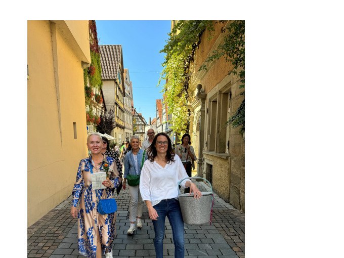 Eine Gruppe von Menschen spaziert fr&ouml;hlich durch eine malerische Altstadtstra&szlig;e mit Fachwerkh&auml;usern und Pflanzen an den W&auml;nden., &copy; Eigenbetrieb Tourismus und Citymanagement Schorndorf
