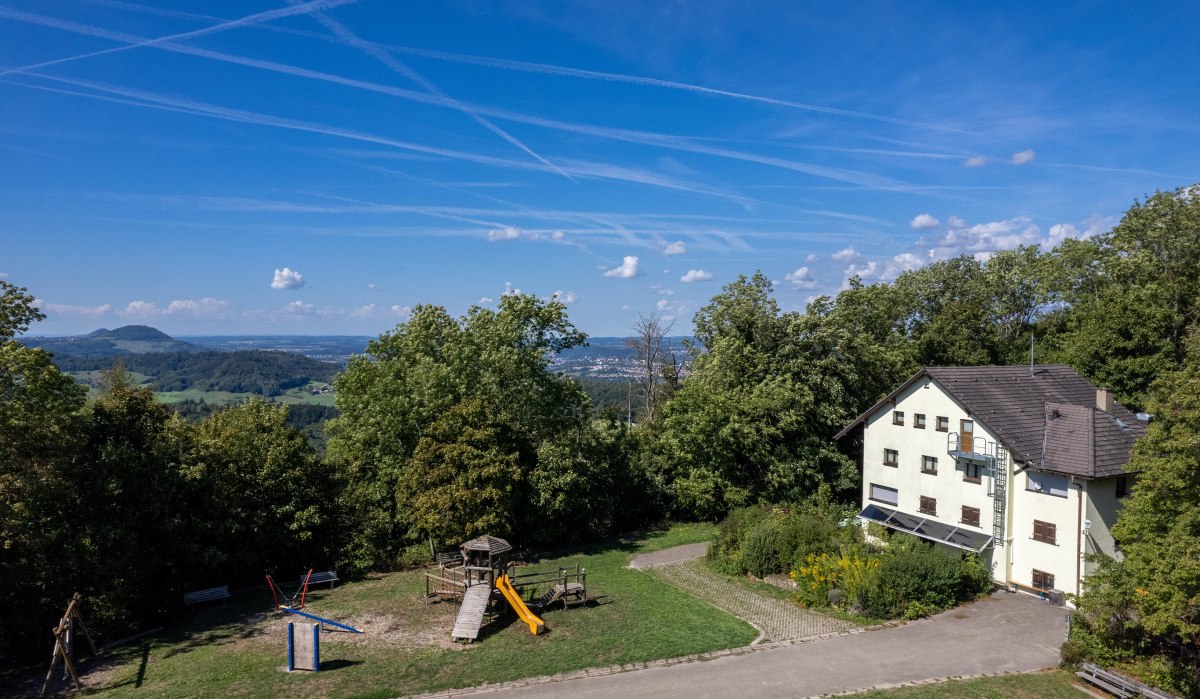 Haus am Waldrand mit Spielplatz, weitem Blick über hügelige Landschaft, blauer Himmel mit Kondensstreifen., © Foto Thomas Zehnder