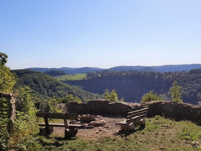 Aussichtspunkt mit zwei B&auml;nken und Feuerstelle, umgeben von gr&uuml;nen H&uuml;geln und W&auml;ldern unter klarem Himmel., &copy; SwabianTravel