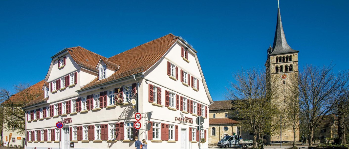 Ein historisches Geb&auml;ude mit roten Fensterl&auml;den in der Altstadt von Sindelfingen. Im Hintergrund ist ein Kirchturm zu sehen, der in den blauen Himmel ragt., &copy; SMG, Sarah Schmid