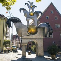 Skulptur der Grauen Pferde in Bietigheim-Bissingen, umgeben von historischen Gebäuden und einem Café mit Tischen und Stühlen im Freien., © Stuttgart Marketing GmbH, Sarah Schmid