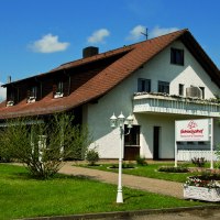 Das Gästehaus Schweizerhof in Böbingen an der Rems, umgeben von einem gepflegten Garten, unter einem klaren blauen Himmel., © Gästehaus Schweizerhof