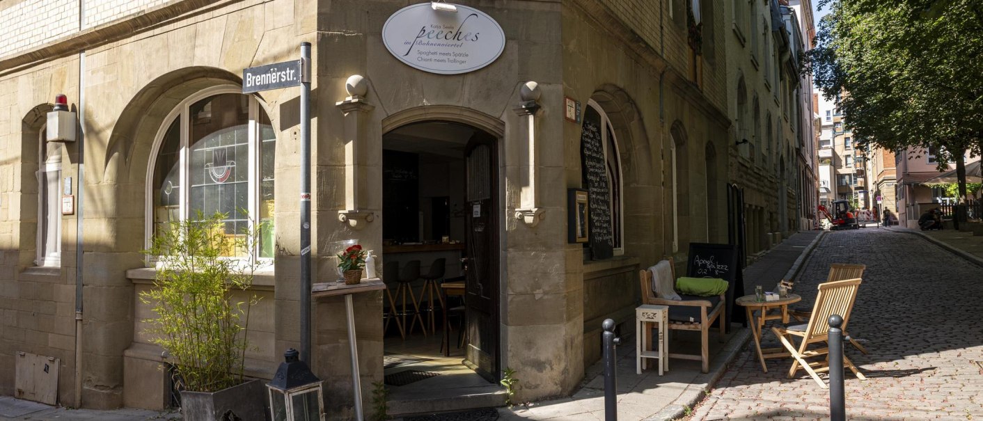 Eingang des Cafés 'Peeches' im Bohnenviertel Stuttgart. Gemütliche Sitzgelegenheiten draußen, Straßenschild 'Brennerstr.' sichtbar., © SMG, Sarah Schmid Eingang des Cafés 'Peeches' im Bohnenviertel Stuttgart. Gemütliche Sitzgelegenheiten draußen, Straßenschild 'Brennerstr.' sichtbar., © SMG, Sarah Schmid