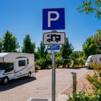 Wohnmobilstellplatz mit zwei geparkten Wohnmobilen und einem Parkplatzschild. Umgeben von Bäumen und sonnigem Wetter., © Stuttgart-Marketing GmbH, Thomas Niedermüller Wohnmobilstellplatz mit zwei geparkten Wohnmobilen und einem Parkplatzschild. Umgeben von Bäumen und sonnigem Wetter., © Stuttgart-Marketing GmbH, Thomas Niedermüller