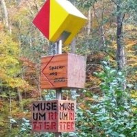 Ein Wegweiser im Wald zeigt den 'Spazierweg' und 'Museum Ritter' an. Bunte Herbstblätter im Hintergrund., © Natur.Nah. Schönbuch & Heckengäu