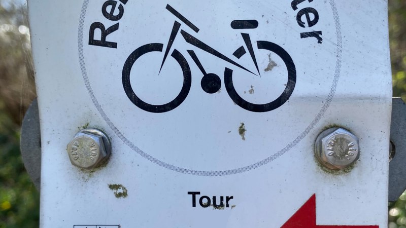 Schild mit 'Remseck-Achter', Fahrradsymbol, 'Tour 1' und rotem Pfeil nach links. Unten das Wappen von Remseck am Neckar.