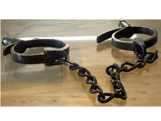 Alte Metallfesseln mit einer Kette liegen auf einem Holztisch. Sie erinnern an historische Methoden der Gefangennahme., &copy; Stadt Besigheim