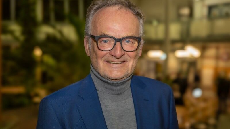 Ein Mann mit Brille und blauem Anzug lächelt in die Kamera. Der Hintergrund ist unscharf und zeigt ein modernes Gebäude., © Stadthalle Leonberg Ein Mann mit Brille und blauem Anzug lächelt in die Kamera. Der Hintergrund ist unscharf und zeigt ein modernes Gebäude., © Stadthalle Leonberg