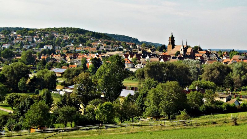 Stadtansicht mit Kirche im Zentrum, umgeben von Häusern und grüner Landschaft. Im Vordergrund sind Bäume und Wiesen zu sehen., © Natur.Nah. Schönbuch & Heckengäu
