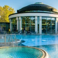 Die Mineraltherme Böblingen zeigt einen dampfenden Außenpool vor einem modernen, runden Gebäude mit großen Glasfenstern., © Stuttgart-Marketing GmbH, Sarah Schmid
