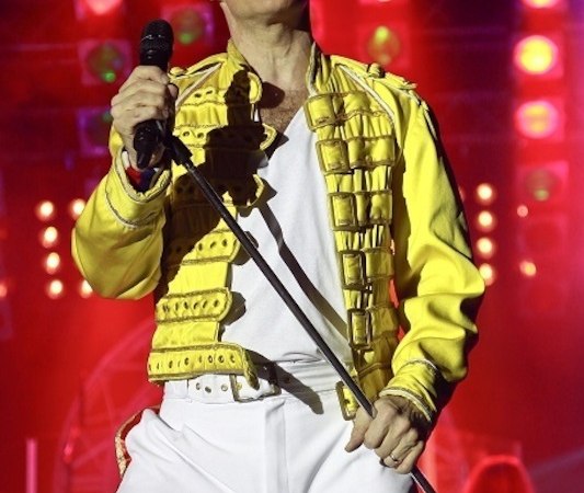 Ein Sänger in gelber Jacke und weißer Hose performt mit Mikrofon auf einer Bühne, umgeben von bunten Lichtern., © die Halle Kulturinitiative e.V. Ein Sänger in gelber Jacke und weißer Hose performt mit Mikrofon auf einer Bühne, umgeben von bunten Lichtern., © die Halle Kulturinitiative e.V.