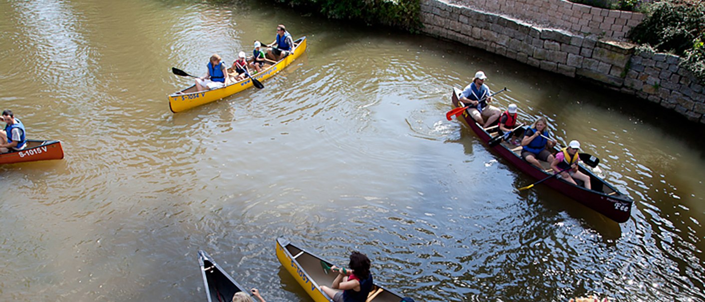 Mehrere Kanus mit Menschen paddeln auf einem Fluss in Waiblingen. Die Teilnehmer tragen Schwimmwesten und genießen die Kanutour., © WTM GmbH Waiblingen
