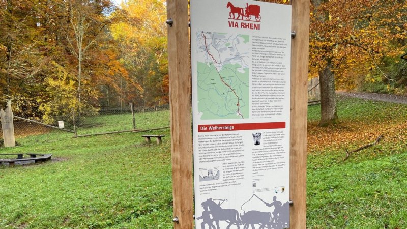 Infotafel "Via Rheni" im Wald, umgeben von herbstlichen B&auml;umen. Die Tafel informiert &uuml;ber die Weihersteige und zeigt eine Karte der Region., &copy; Natur.Nah. Sch&ouml;nbuch & Heckeng&auml;u