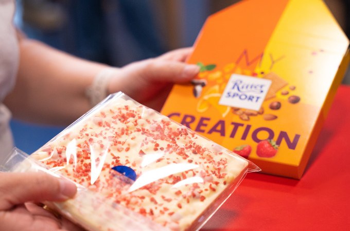 Person h&auml;lt eine Tafel wei&szlig;e Schokolade mit roten Streuseln und eine Verpackung mit 'My Creation' von Ritter Sport., &copy; Alfred Ritter GmbH &amp; Co. KG | Waldenbuch